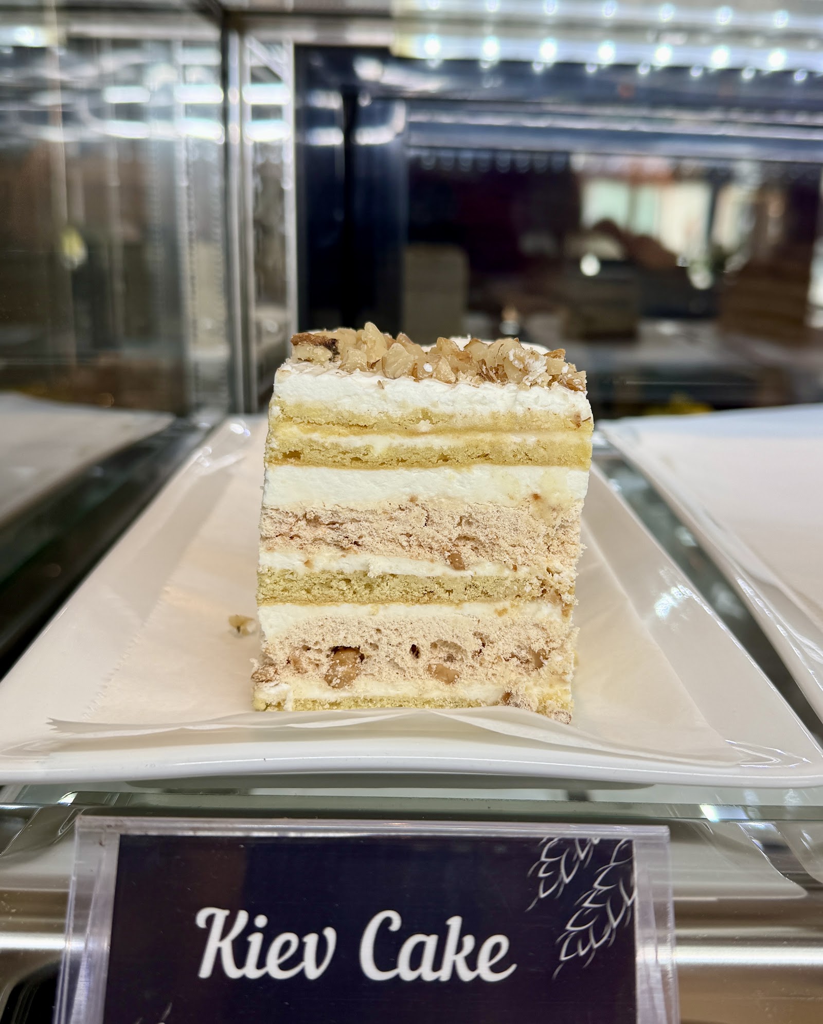 A tall slice of layered cream cake on a white plate