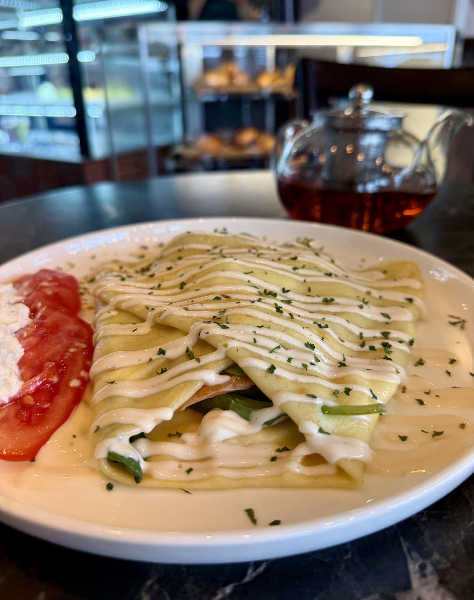 Rolled crepes with sauce and a small pot of tea